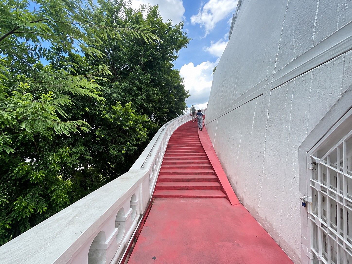 Steep red steps along the white wall of Phu Khao Thong
