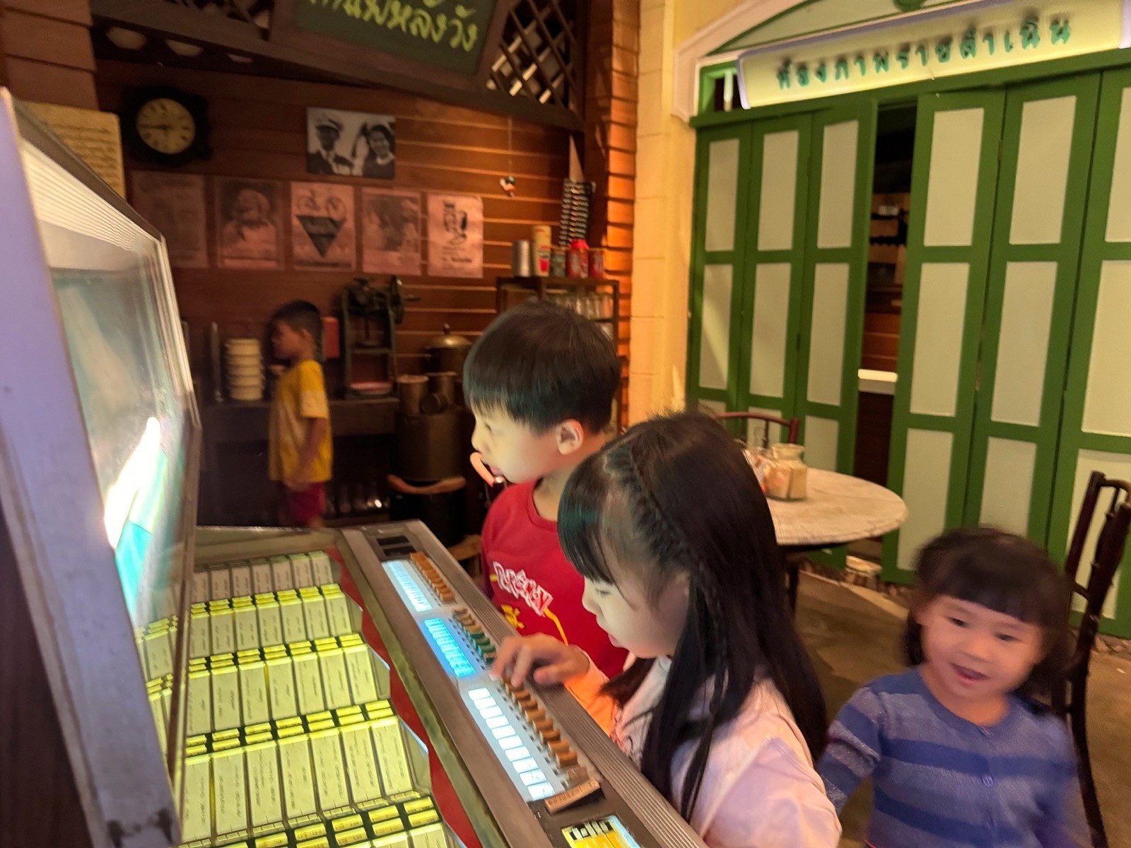 Children trying the vintage jukebox in a recreated Bangkok shop