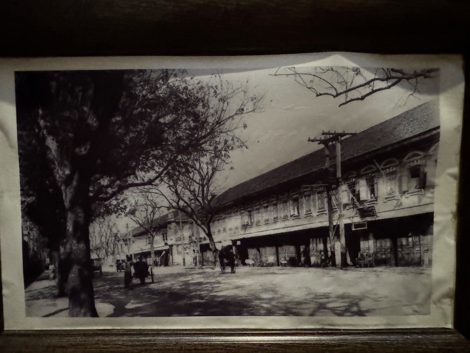Historic black-and-white photograph of a Bangkok street lined with old shophouses